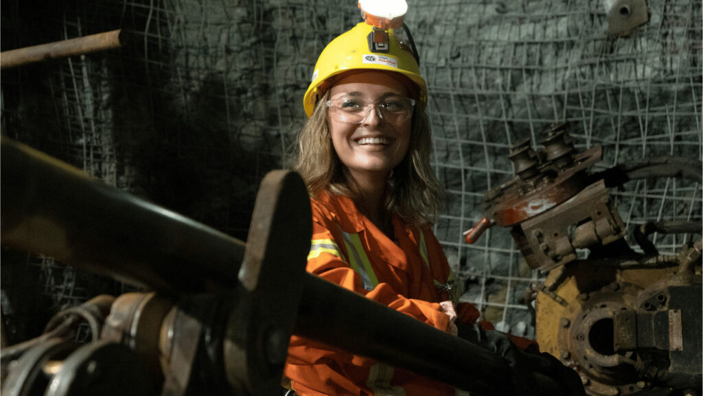 A female driller smiles as she operates the autonomous drill rig.